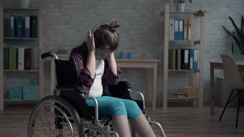 Young Child Looking Distressed in Wheelchair Indoors