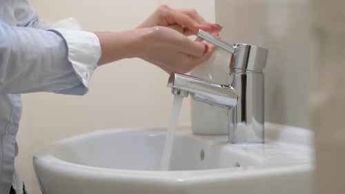 Person Washing Hands at Sink in Bathroom