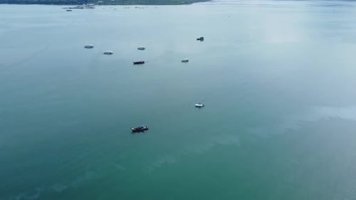 Aerial view from a drone of Thai traditional longtail fishing boats sailing in the tropical sea.