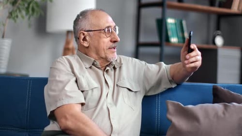 Senior Man Video Calling on Smartphone in Living Room