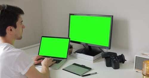 Beau photographe indépendant regardant un ordinateur portable, tapant sur le clavier. Retouche de photos