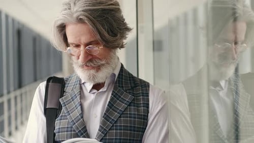 Mature Businessman in Suit Reading in the Airport Terminal