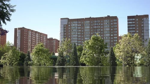 Schöner Teichpark, grüne Bäume und Stadthäuser