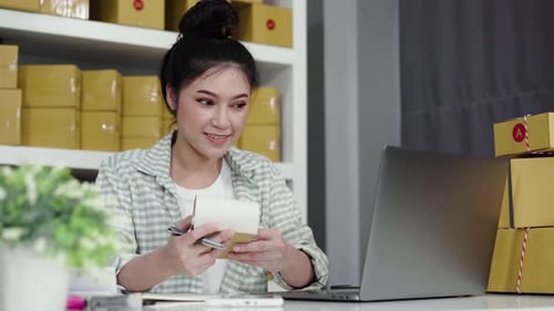 happy woman working with her laptop computer and courier parcel box at home office