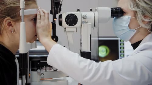Der Augenarzt untersucht das Auge des Patienten und schaut dann in die Kamera