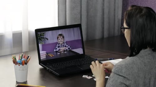 Woman Teaching Child via Laptop Online