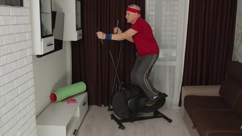 Active Senior Man Exercises on Stationary Bike at Home
