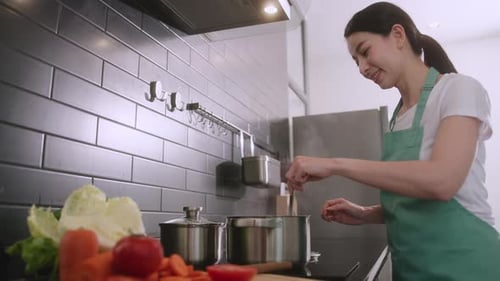 Woman Cooking and Tasting Food in Kitchen