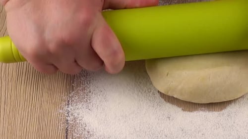 Hands Rolling Dough With Rolling Pin on Flour