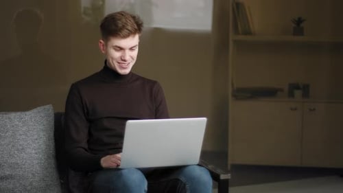 Young Adult on Laptop in Living Room Chatting