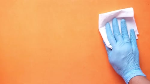 Hand Disinfects Bright Orange Surface with Wipe