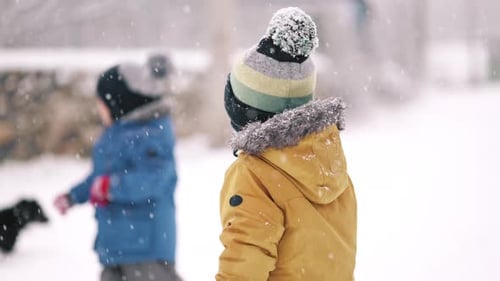 Happy Twins Kleinkinder Jungen haben Spaß und spielen mit Hund auf winterlichem Schneefall-Hintergrund