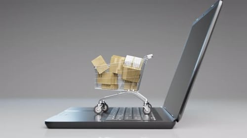 Conceito de compras pela internet. Carrinho cheio de pacotes colocados no laptop aberto.