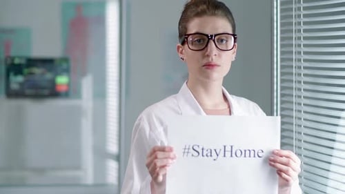 Woman in Lab Coat Holding Stay Home Sign