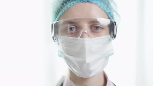 Eine Ärztin in medizinischer Uniform schaut im Krankenhaus aus nächster Nähe in die Kamera