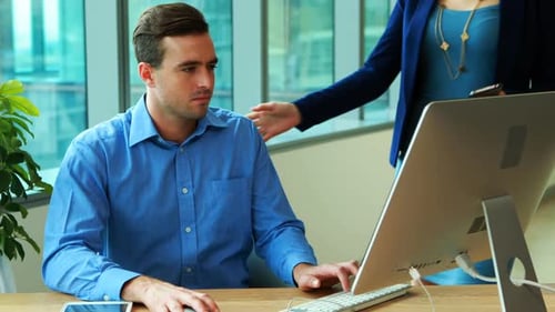 Man Working at Computer Talks to Redhead Woman