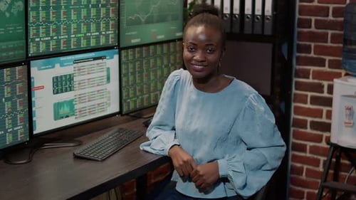 Retrato de una mujer bróker que usa monitores múltiples para observar el mercado comercial