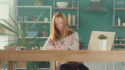 Adolescente pelirroja estudiando en casa en línea viendo un Vídeo tutorial