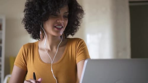 Woman working at home on laptop with earphones