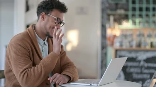 Man Video Conferencing On Laptop in Cafe
