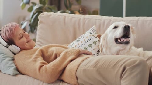Woman Relaxing on Couch, Petting Happy Golden Retriever