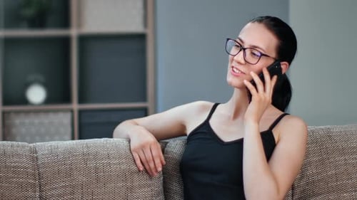 Woman on Phone Sitting on Couch at Home