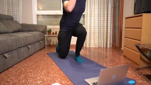 Man Exercising in Living Room with Laptop