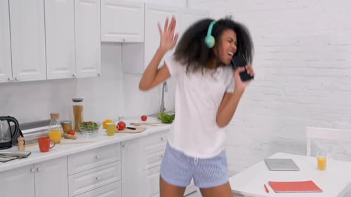 Young Woman Dancing and Singing in Kitchen