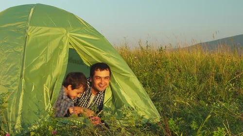 Father and Son Camping Together in Grassy Field