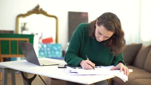 Woman Working at Home with Laptop and Paperwork