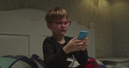 Boy Plays on Smartphone in Bedroom