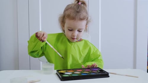 Child Painting with Watercolors at Table Indoors