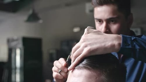 Male Barber Giving a Haircut in Barbershop