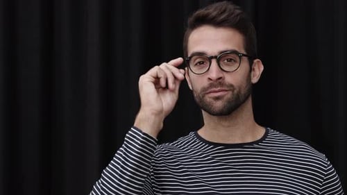 Young Man Puts on Glasses and Smiles