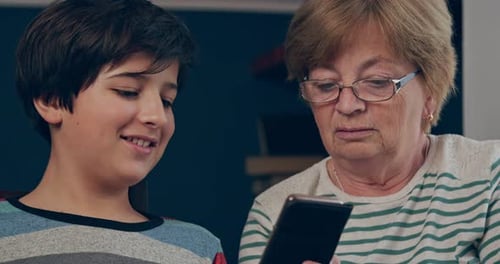The Grandson Teaches His Grandmother to Use the Smartphone