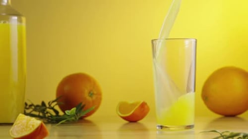 Orange Juice Being Poured in Glass on Yellow