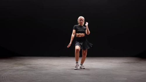 Alluring Young Woman Dancing in Studio Against Black Background