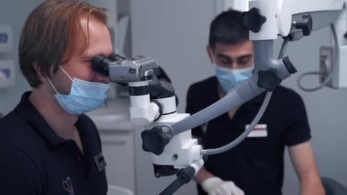 Dentist working behind microscope. Doctor using the dental microscope in the clinic