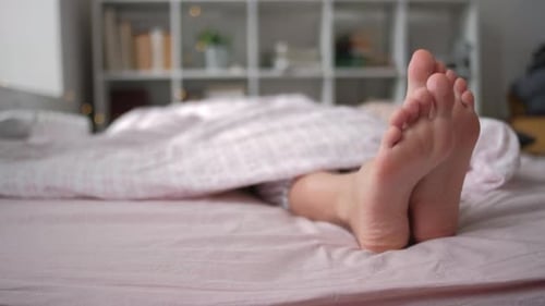 Closeup View of Feet Lying on Soft White Pillow at Bed