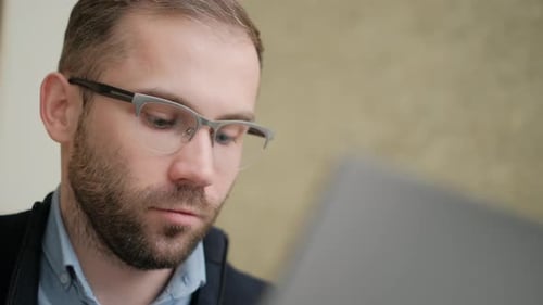 Man Wearing Glasses Looks at Computer Screen