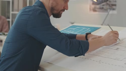 Architect Working on Building Plans in Office