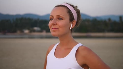 Active Healthy Lifestyle And Technology Concept. Woman In Bluetooth Earphones On Beach.