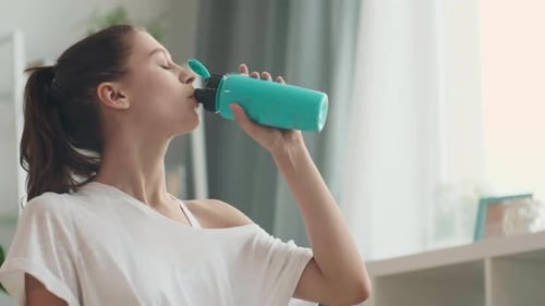 Brunette Woman Drinks Water in Sunny Home