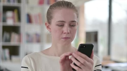 Woman Using Smartphone in Bright Indoor Setting