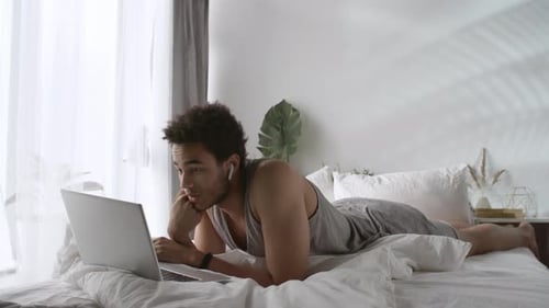 Young Adult Relaxing in Bed with Laptop