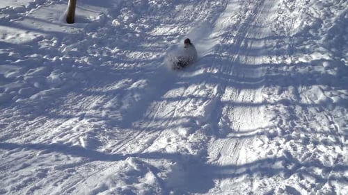 The girl rides a snow slide on sledges. Slow motion.
