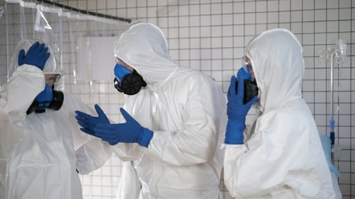 Un equipo de médicos con ropa protectora discute entre sí.