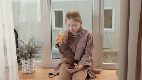 Girl Drinking Juice and Looking at Phone