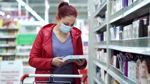 Mulher escolhendo chocolates em supermercado durante a pandemia
