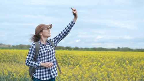 Woman Uses Phone in Field of Yellow Flowers